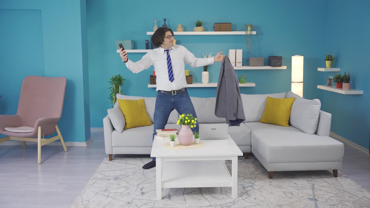 집에 있는 슈트 입은 남자가  ⁇ 드폰을 들고 재미있게 춤을 추고 있습니다.