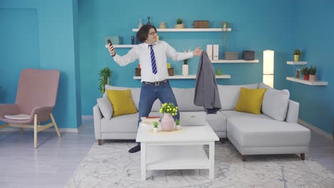 el hombre de traje en casa está bailando graciosamente con el teléfono en la mano, divirtiéndose.