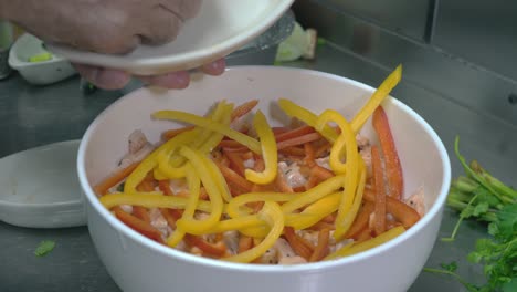 up close shot of chef hands putting different bell peppers in bowl