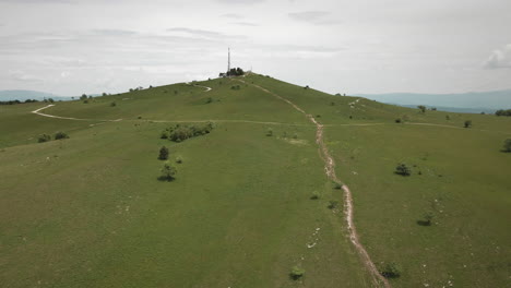 drone shot of the top of mountain slavnik with green meadows and off road paths to the top where is radio tower