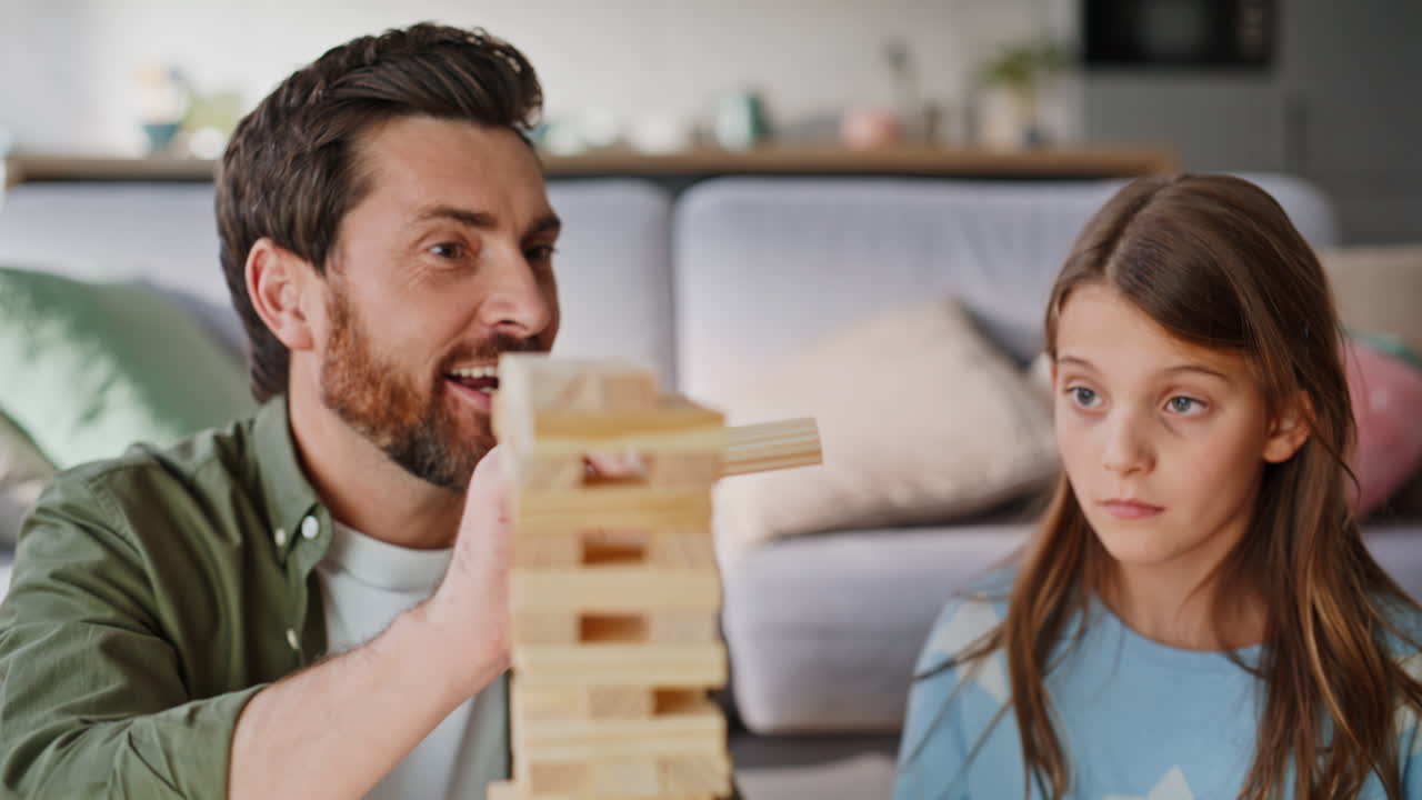 Primo piano di genitore e figlio che si divertono a costruire una torre con blocchi di legno in soggiorno
