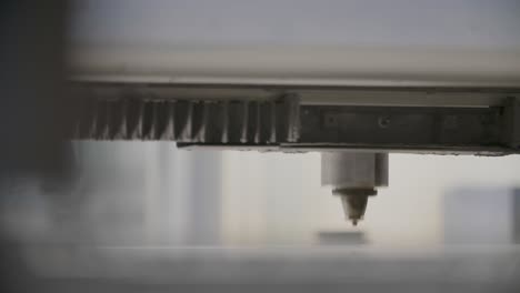 primer plano de una máquina de corte por láser en funcionamiento con luz enfocada cortando a través del material