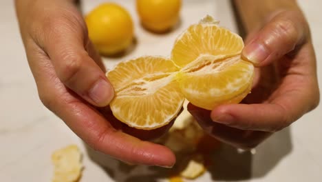 Hands peeling and splitting an orange