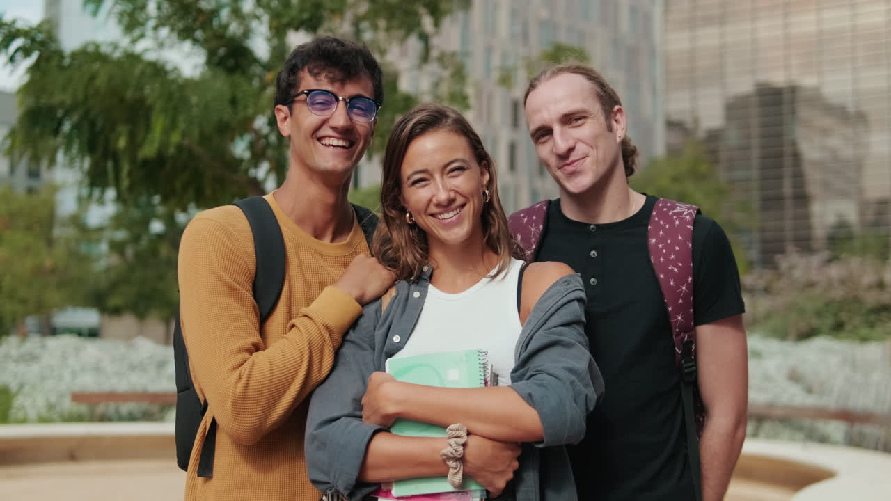 Two male students and their female friend smiling at camera