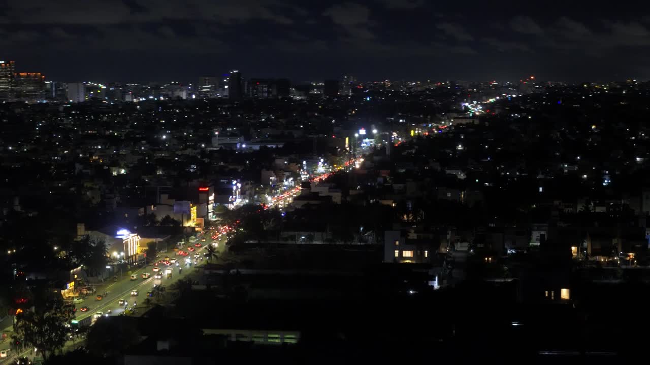 Drone pan shot of cityscape during nighttime. Lit up roads.