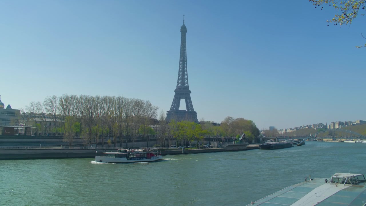 Torre Eiffel a Parigi, fiume Senna, argine con barca come sfondo, scatto a mano libera. Vista panoramica del simbolo francese con nave da crociera che transita lungo il lungofiume cittadino.