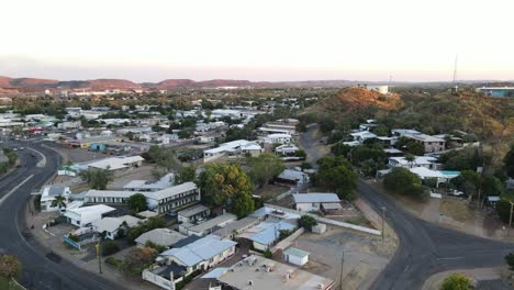 Drone-aerial-of-Mount-Isa-town-moving-forward-down-during-sunrise-showing-mountains