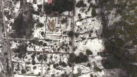 top-down aerial view of small snowy colonia suiza settlement and its snowy forested site, bariloche, argentina
