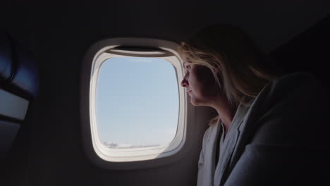 una mujer joven mira por la ventana del avión que comienza a acelerar a lo largo de la pista de inicio de