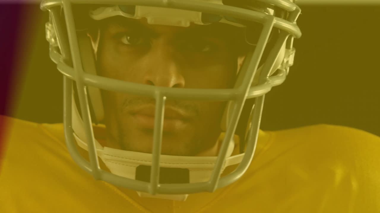 Giocatore di football americano che tiene un pallone, la telecamera si sposta verso l'alto, bagliori colorati che rivelano uno sguardo concentrato per una pubblicità sportiva