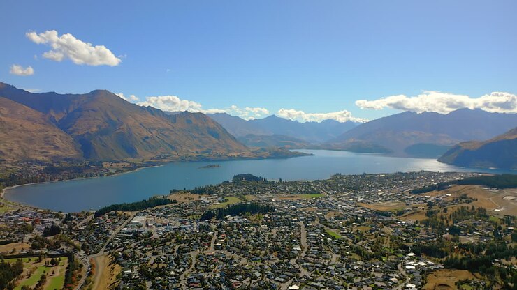 Il Lago Wanaka, Nuova Zelanda, è un lago glaciale con il villaggio turistico di Wanaka lungo la riva - ripresa aerea in allontanamento