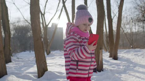 Child-girl-blogger-making-video-call-on-mobile-phone,-selfie-photo-for-social-networksin-winter-park