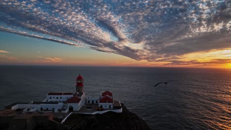 a close-up aerial view of the lighthouse with soft sunset light illuminating its red top.