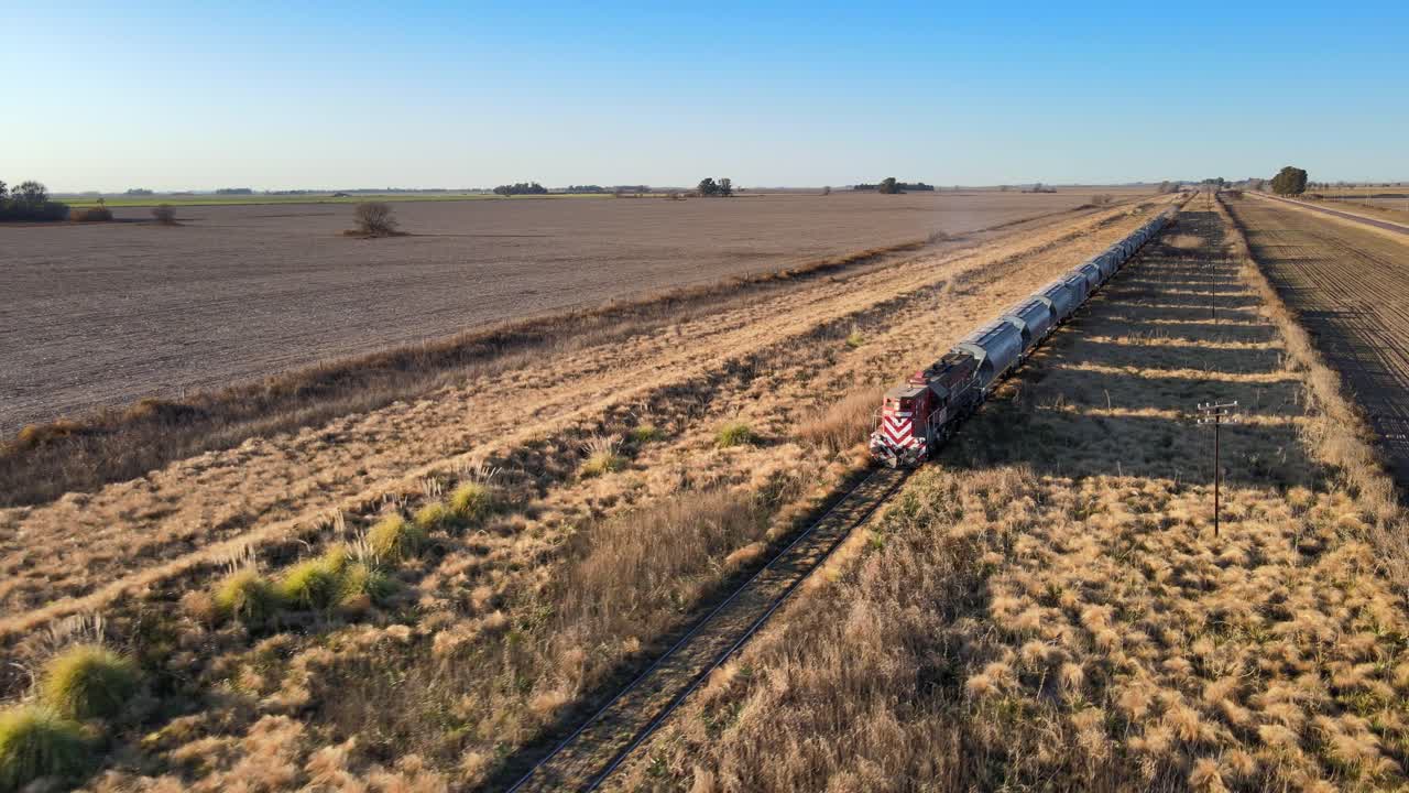 Aerial medium front view tracking long train hauling grain through Argentina vast La Pampa countryside
