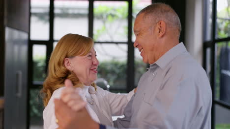 happy senior couple dancing in their home kitchen