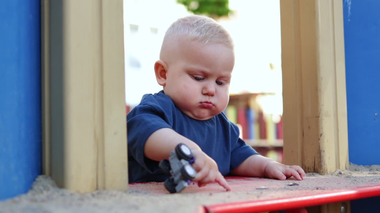 Baby boy playing with sand outdoors. Child development. Children's games on the playground