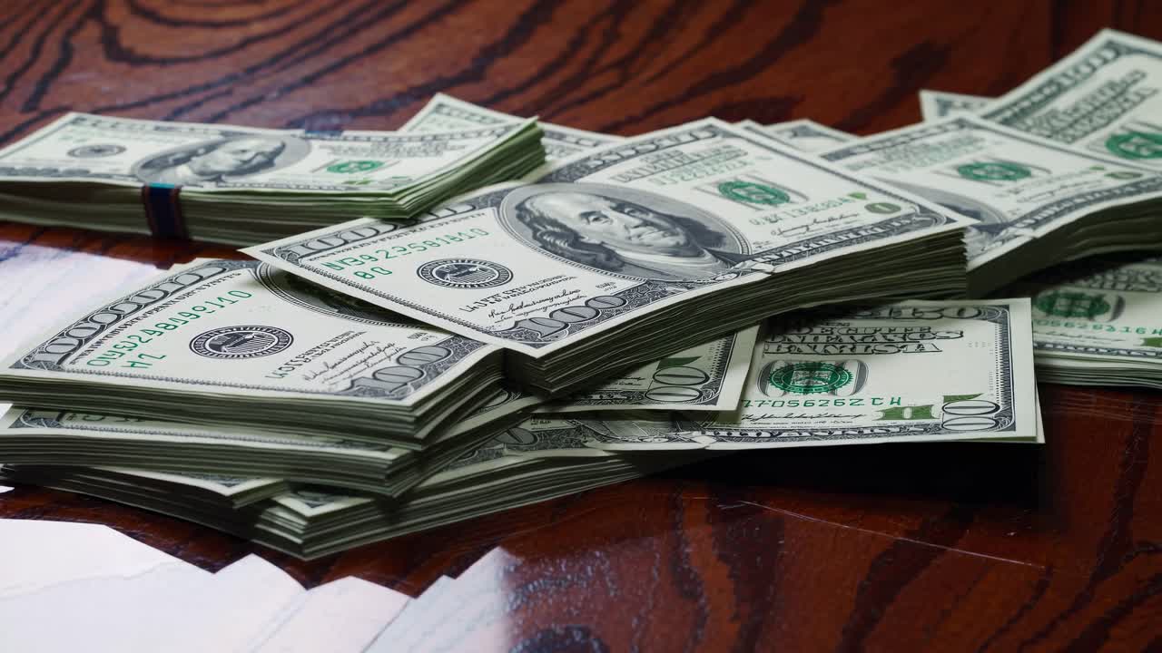 Stacks of US dollar bills on a wooden table, captured from a low-angle view, ideal for a finance