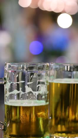 two beer glasses with blurred night lights