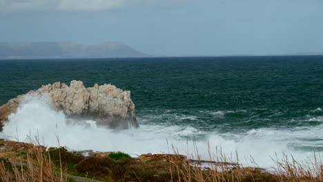 turbulent waves crash into rocky hermanus coastline