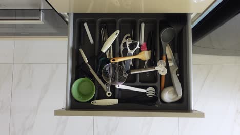 inside a kitchen drawer filled with utensils