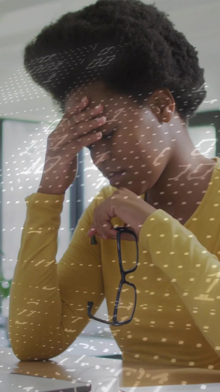 Vertical video: Woman reading laptop papers with specs rubbing head dot overlay showing work stress