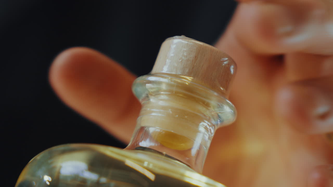 Close up shot of plastic sealing a lid on a glass bottle of distilled gin, industrial process in a gin distillery production