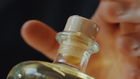 close up shot of plastic sealing a lid on a glass bottle of distilled gin, industrial process in a gin distillery production