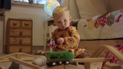 zoom in - cute baby watching a toy train before managing to catch and study it