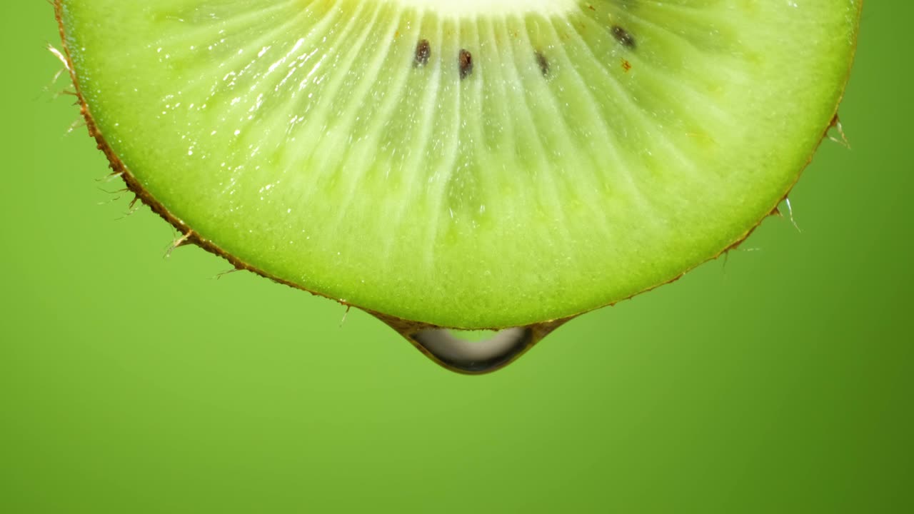 키위 조각의 근접 또는 매크로, 물방울이 느린 동작으로 떨어집니다.