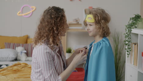 mother helps child put on superhero costume