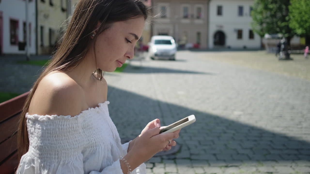 joven usando un teléfono inteligente en la plaza de la ciudad