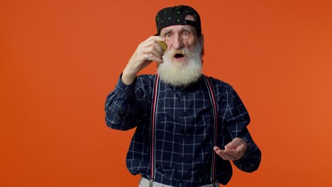 smiling old man in a plaid shirt and suspenders holding a coin