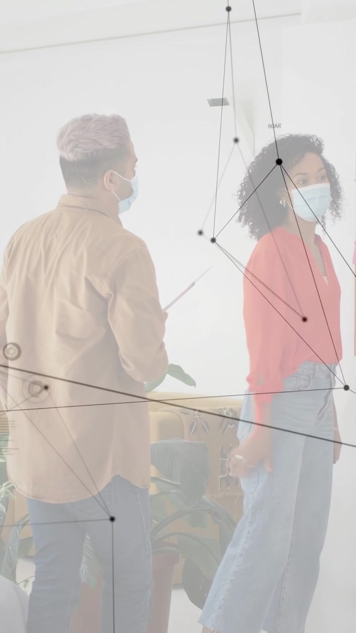 Vertical video: Right woman reaching tech grid, left man with folder noting marks while HUD masking