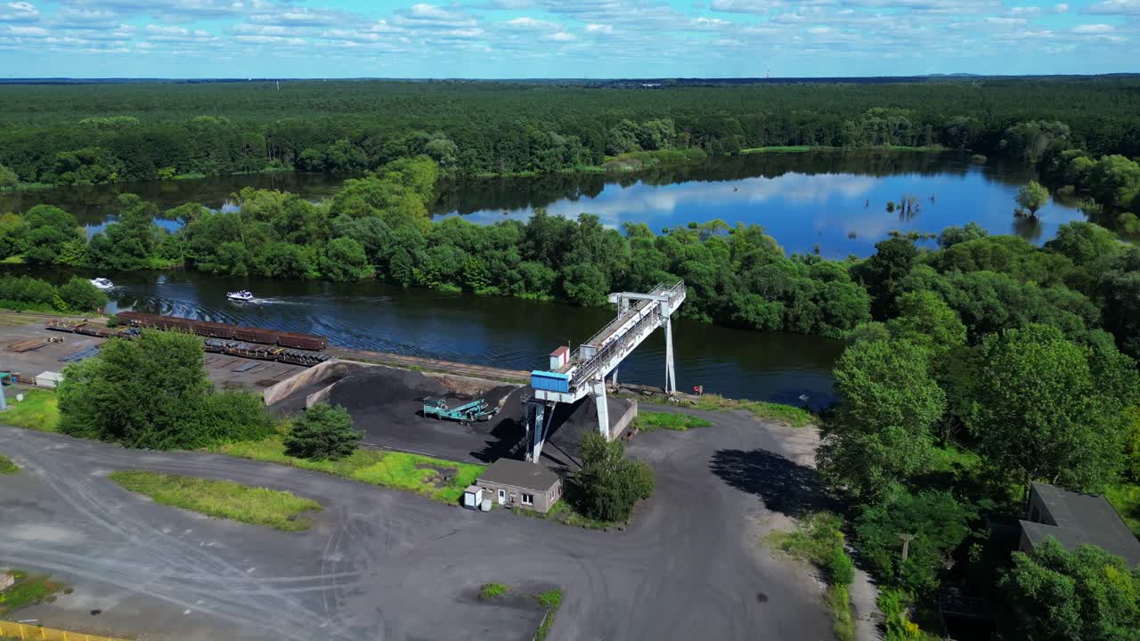 Gantry crane transporting scrap metal at Hennigsdorf electric steel mills on a sunny summer day. Majestic aerial view flight fly reverse drone