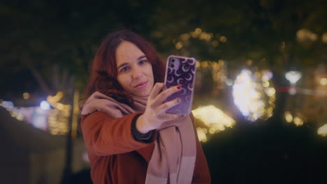 Una-Chica-Se-Toma-Una-Selfie-Con-Su-Teléfono-Inteligente-En-Un-Mercado-Navideño-Cerca-De-Un-Tiro-De-Cardán-En-Cámara-Lenta