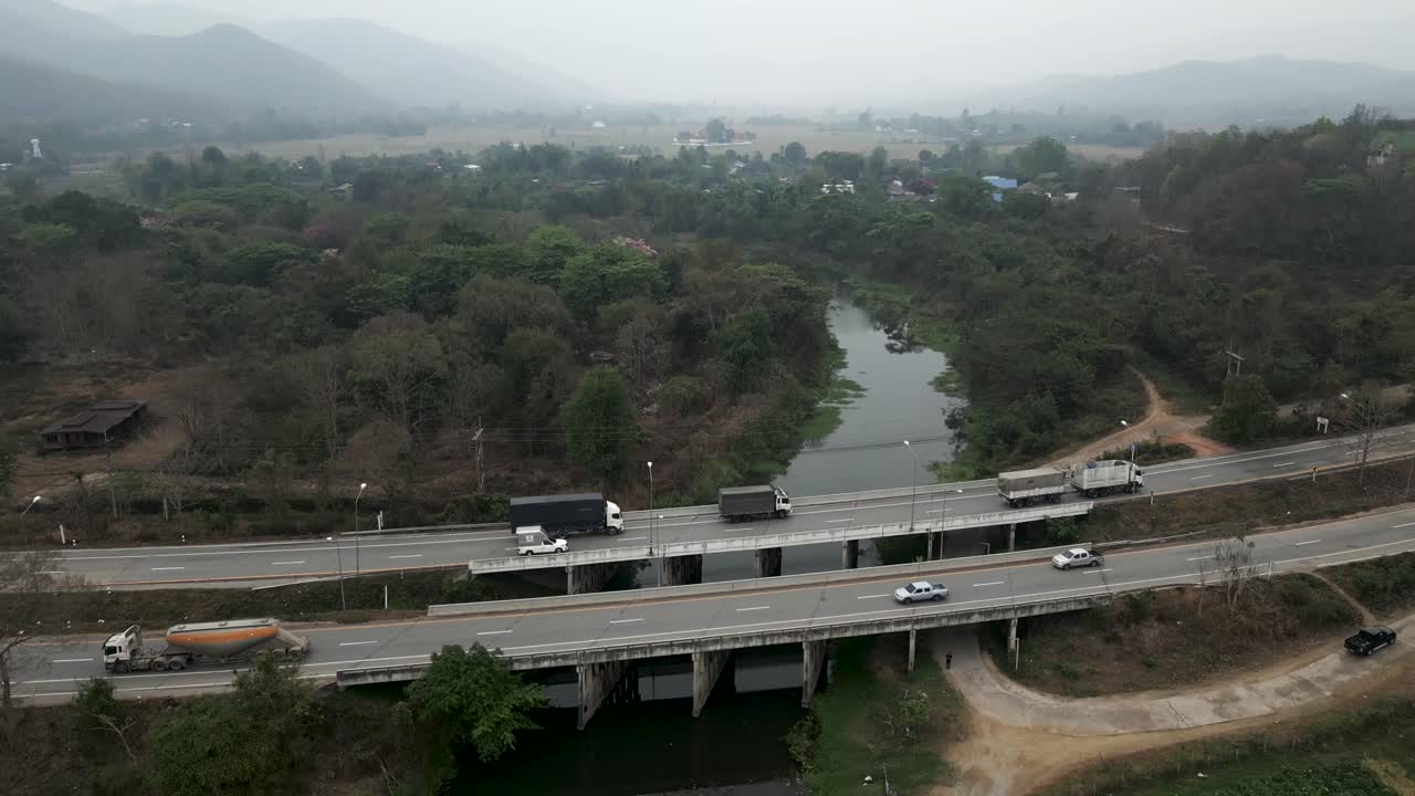 Aerial view of a highway with bridges, trucks, and cars in a rural landscape