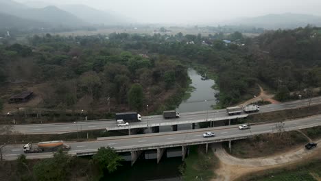 aerial view of a highway with bridges, trucks, and cars in a rural landscape