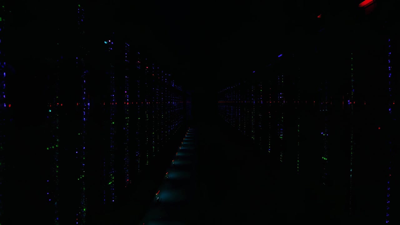 Pulsing server rack LEDs showing status in server room aisle from system heartbeat with cables