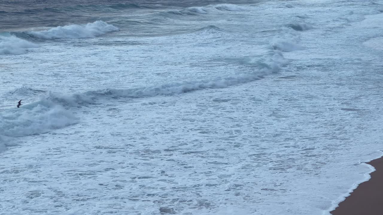 A tranquil beach at sunset where relaxed bathers enjoy the calming waves and warm evening light