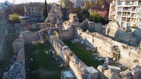 Drohne,-Die-Neben-Der-Alten-Römischen-Ruine-In-Europa-Abhebt,-Während-Weiße-Vögel-Vorbeifliegen