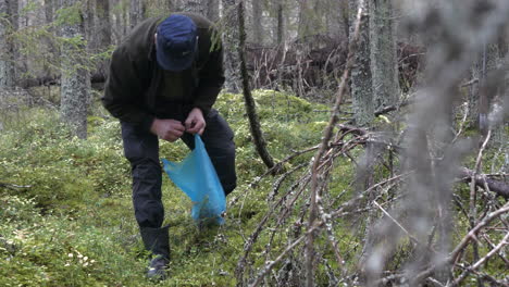 Senior-caucasian-man-gathers-mushrooms-from-forest-floor,-handheld