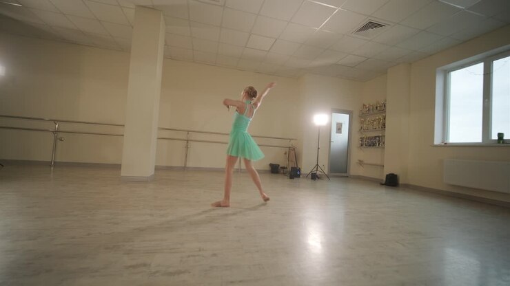 Un gruppo di giovani allievi di danza classica in abbigliamento da ballo nero che eseguono esercizi in un ampio studio di danza con pavimenti in legno e barre a muro. Espressioni concentrate e movimenti sincronizzati