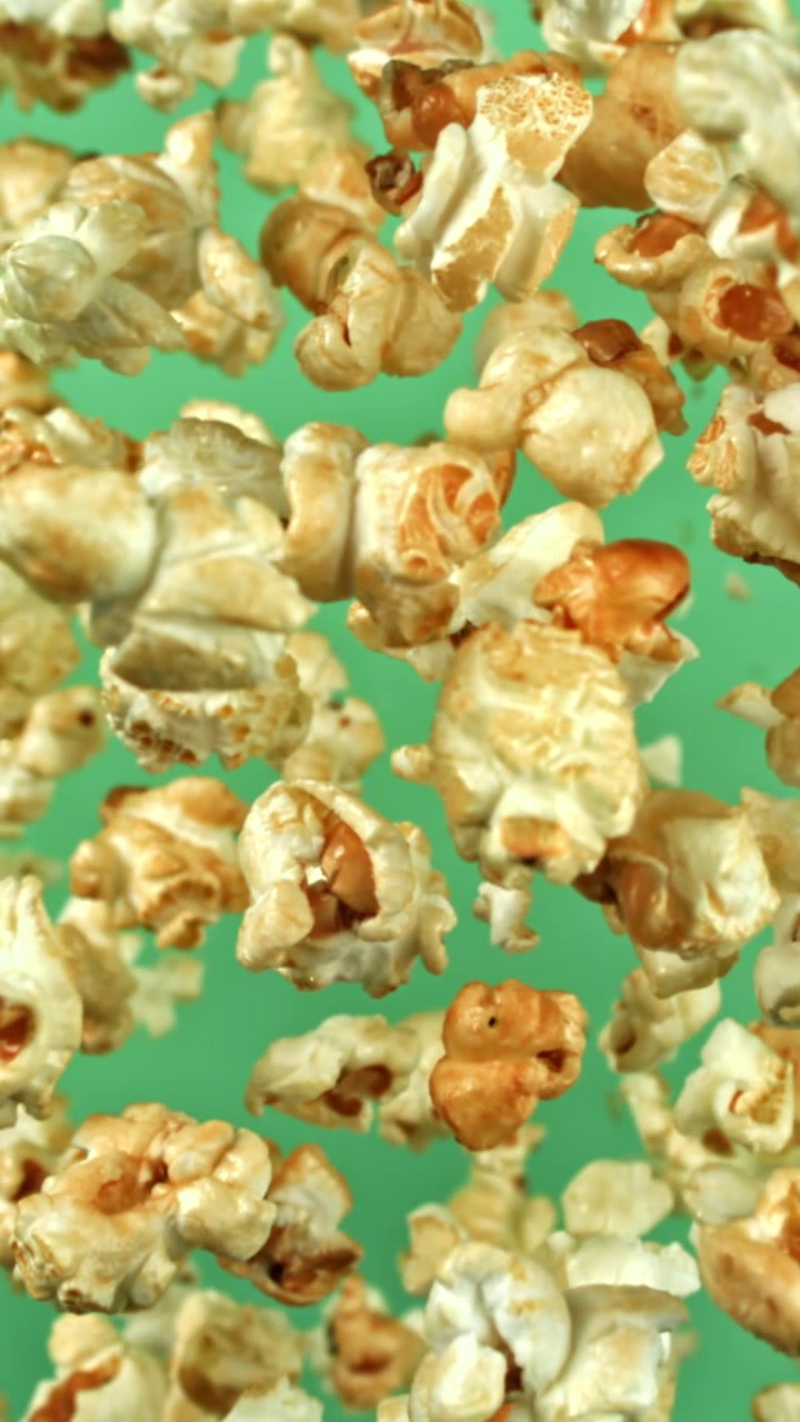 Popcorn delizioso che galleggia al rallentatore su sfondo verde