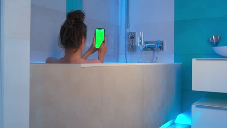 green screen, chromakey of phone. lonely girl with smartphone in bath watching content or shopping online