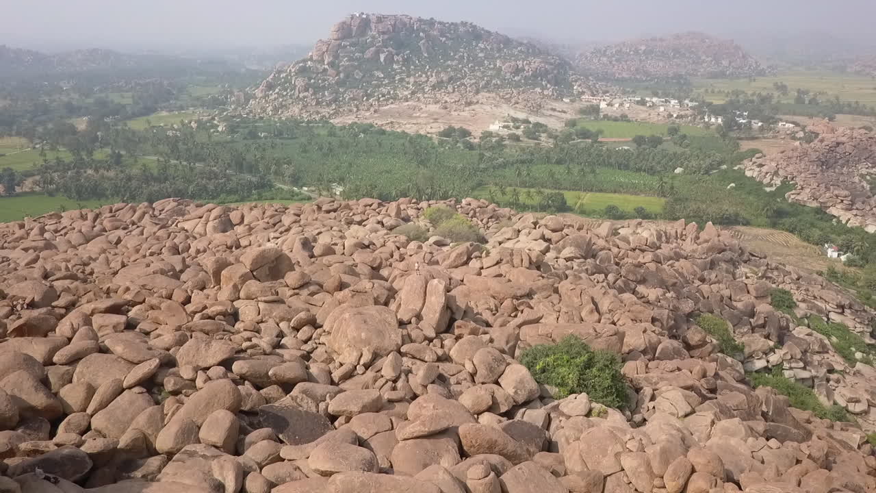 Un uomo solitario è perso tra le pile giganti di enormi pietre ad Hampi, India.