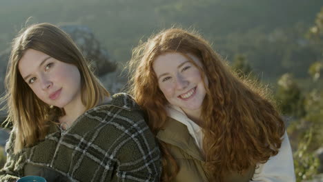 portrait of two girls talking and laughing outdoors, then looking at camera and smiling