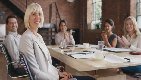 portrait of a confident young business woman  at boardroom table in slow motion turning around and smiling