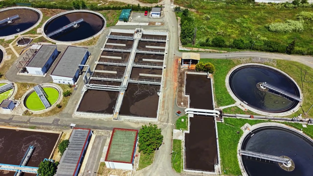 Water treatment facility operates in a large area with multiple tanks and buildings during daytime