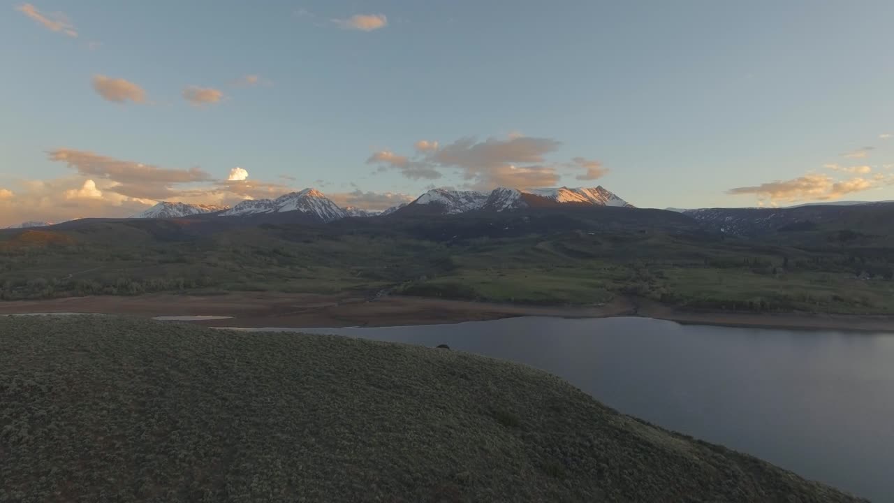 hermosa puesta de sol boom pan up establecimiento disparo sobre la ladera de la montaña en las montañas rocosas cubiertas de nieve y el lago