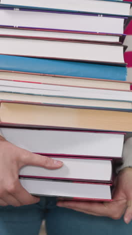 heavy textbook pile in woman hands closeup. bookworm carries huge stack of literature walking across library. librarian works with books in storage